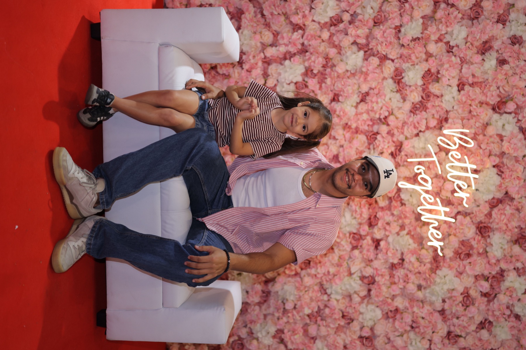 Pareja posando frente al muro floral
